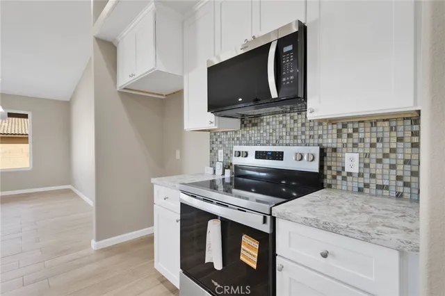 a large white kitchen with kitchen island a sink stainless steel appliances and cabinets