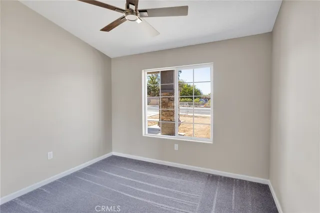 an empty room with a ceiling fan and carpet