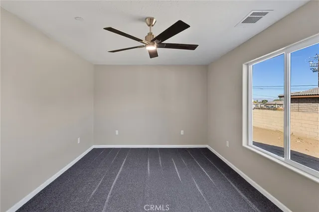 an empty room with wooden floor a ceiling fan and windows