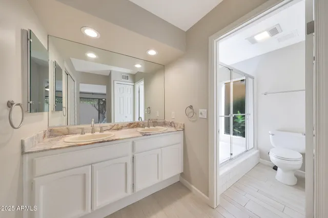 a bathroom with a double vanity sink toilet and shower