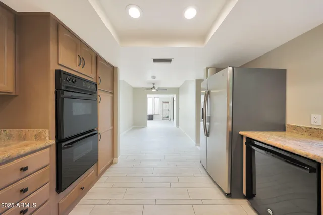 a view of a refrigerator in kitchen and an empty room with wooden floor