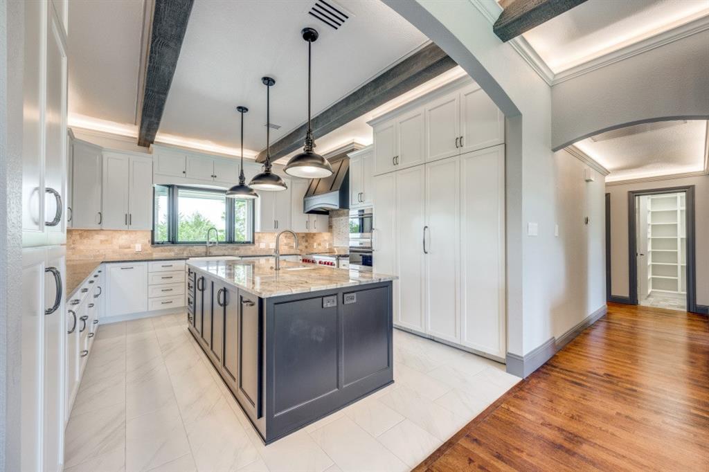 3244 Joe Davis Road Whitewright, TX 75491 - Photo 5 of 28 Kitchen featuring arched walkways, light stone counters, decorative backsplash, an island with sink, and crown molding