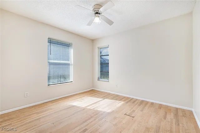 an empty room with windows and ceiling fan