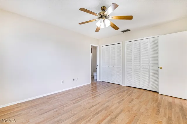 an empty room with wooden floor fan and windows
