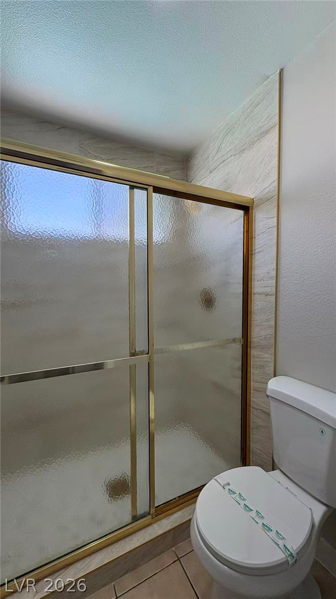 4325 Newcastle Road Las Vegas, NV 89103 - Photo 16 of 18 A full bathroom features a stand-up shower with sliding glass doors and a pristine commode.