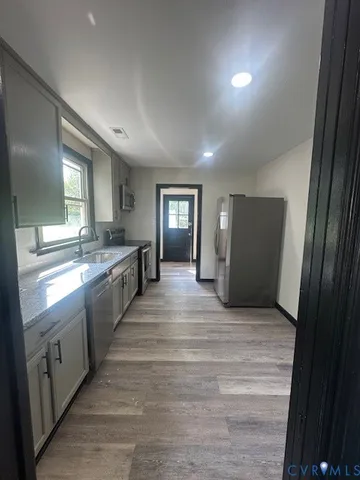 a large kitchen with a sink and dishwasher a refrigerator with wooden floors