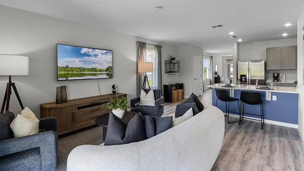 a living room with furniture a flat screen tv and kitchen view