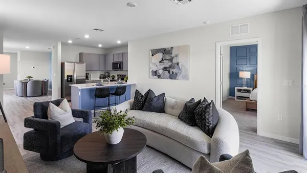 a living room with furniture potted plant and kitchen view