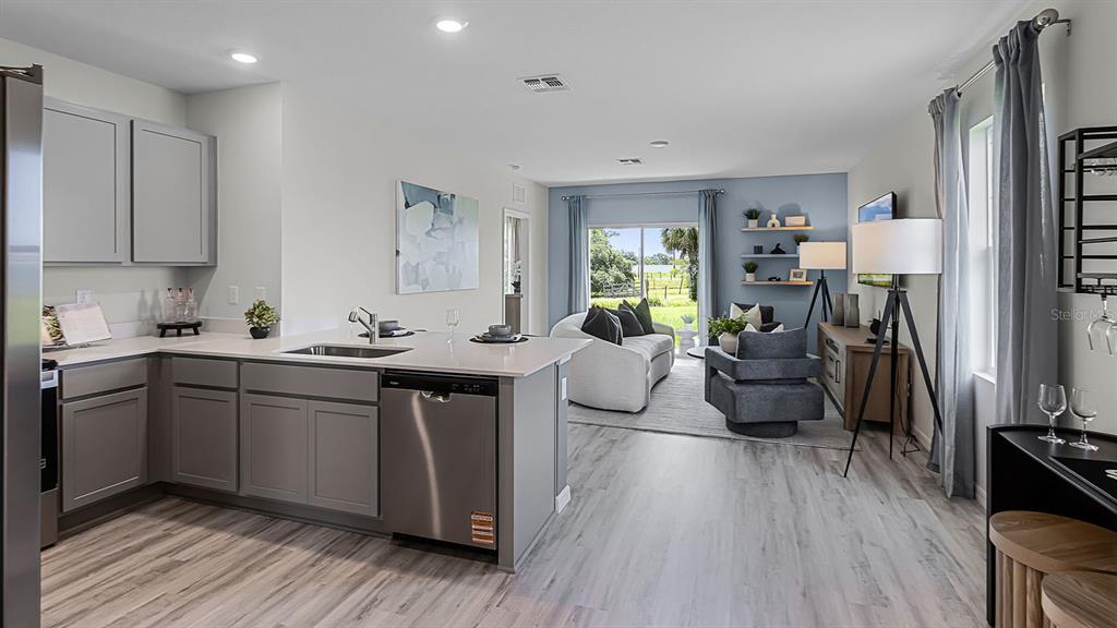 3316 White Indigo Road Winter Haven, FL 33884 - Photo 4 of 27 a kitchen with a sink dishwasher a stove and a refrigerator with wooden floor