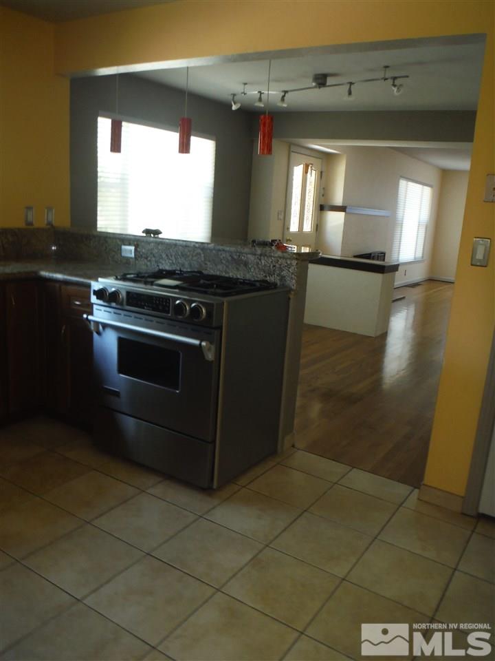 675 Robin Street Reno, NV 89509 - Photo 2 of 7 a kitchen with granite countertop a stove a sink and a mirror