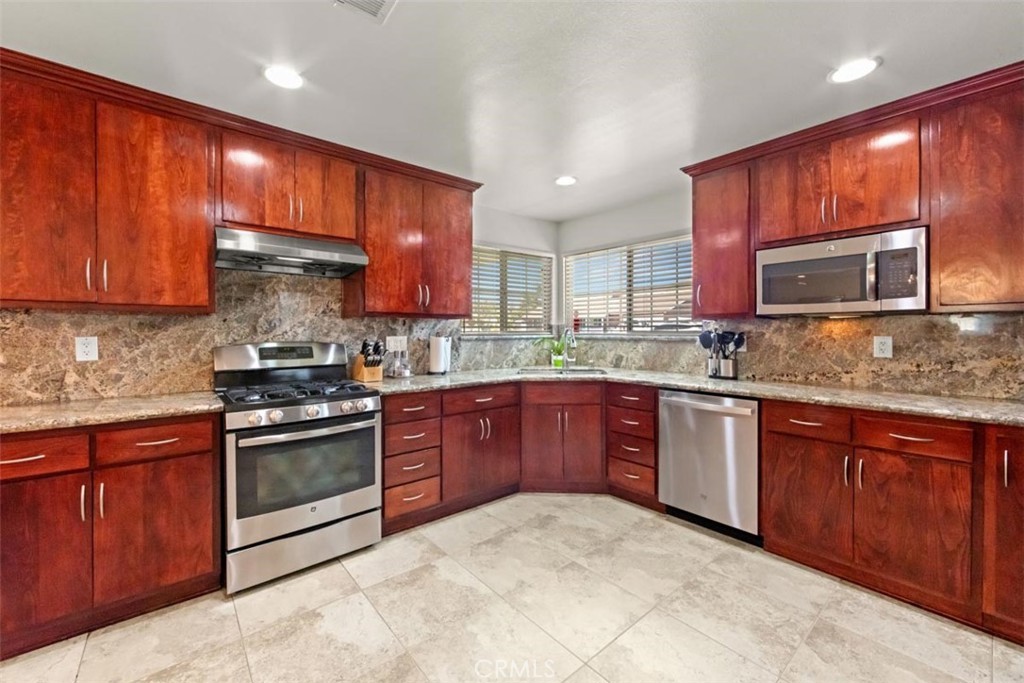 3275 Dalhart Avenue Simi Valley, CA 93063 - Photo 11 of 41 a kitchen with stainless steel appliances granite countertop wooden cabinets a stove top oven a sink and dishwasher