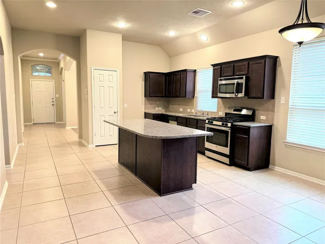 a kitchen with stainless steel appliances a sink a stove a microwave a counter top space cabinets and flat screen tv
