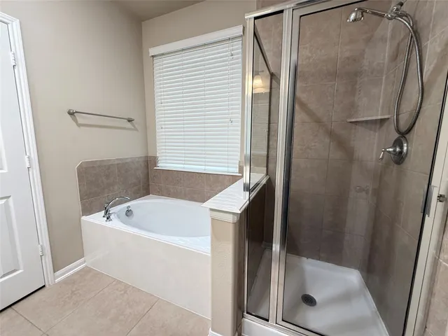 a bathroom with a tub a mirror and a shower