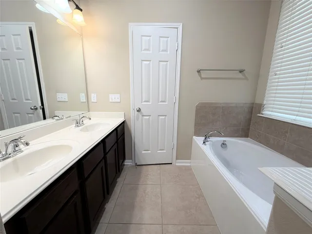 a spacious bathroom with a tub sink and mirror