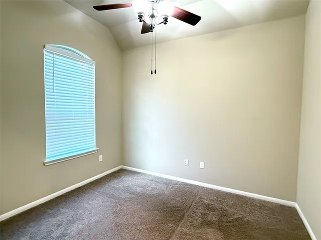 an empty room with a window and a ceiling fan