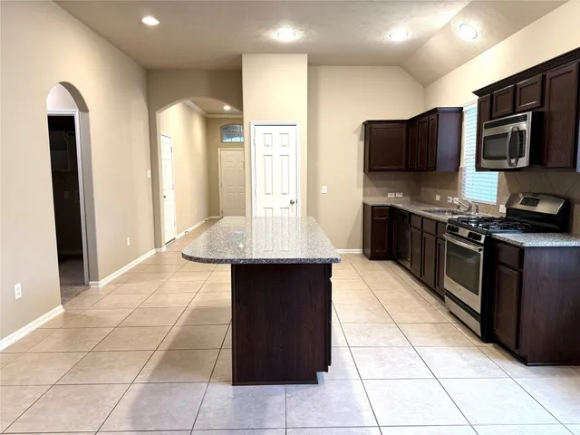 a kitchen with stainless steel appliances a stove a sink a microwave and a refrigerator