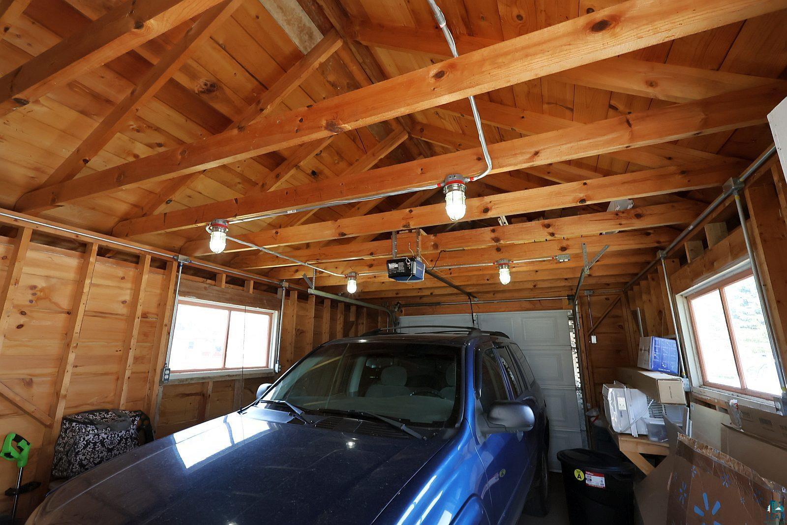 83185 Washington Avenue Port Wing, WI 54865 - Photo 6 of 26 Garage interior featuring exposed wood framing and ceiling, multiple windows, and overhead lighting fixtures
