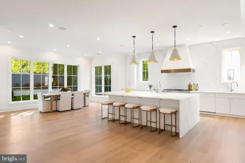 a large white kitchen with a large island oven a sink dishwasher and white cabinets next to a window