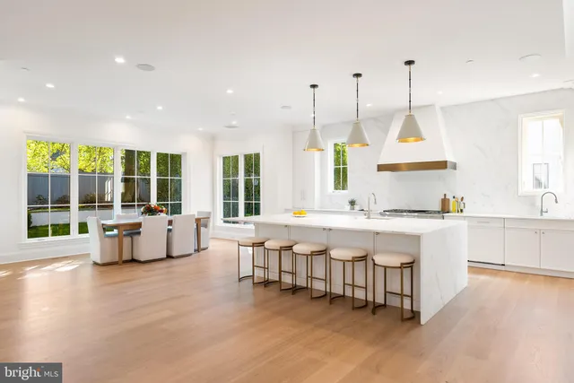 a large white kitchen with a large island oven a sink dishwasher and white cabinets next to a window