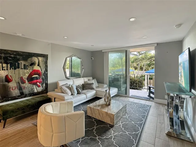 a living room with furniture a flat screen tv and a floor to ceiling window