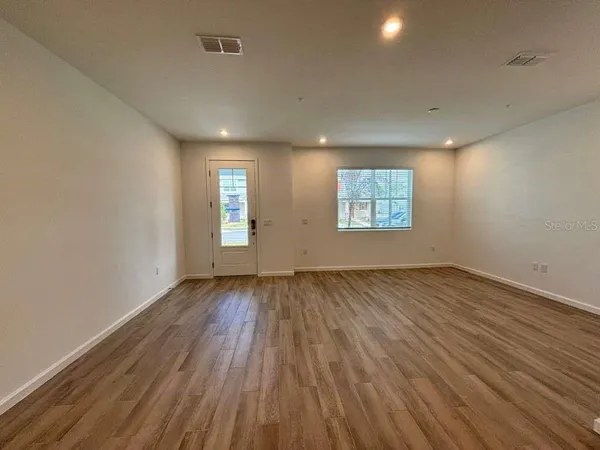 an empty room with wooden floor and window