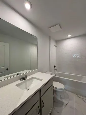 a bathroom with a sink a toilet and a large mirror