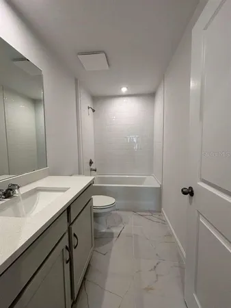 a bathroom with a granite countertop sink a toilet and shower