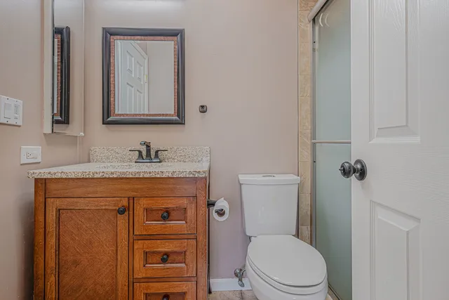 a bathroom with a granite countertop toilet sink and mirror