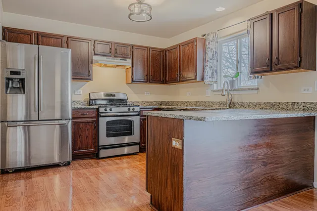 a kitchen with granite countertop a sink stainless steel appliances and cabinets