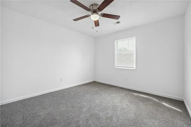 an empty room with a window and a ceiling fan