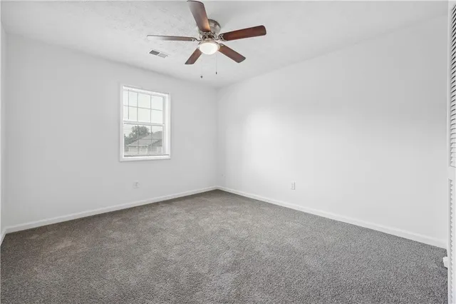 an empty room with a window and a fan
