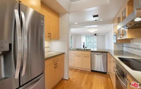 a kitchen with stainless steel appliances granite countertop a refrigerator a sink and white cabinets