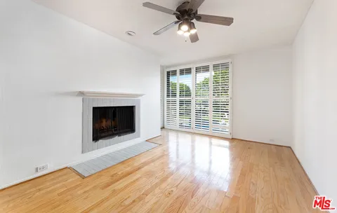 a view of an empty room with wooden floor fireplace and a window