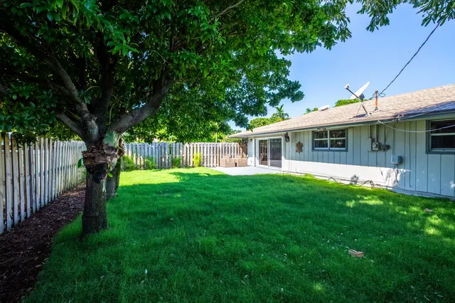 a view of a house with a backyard and a large tree