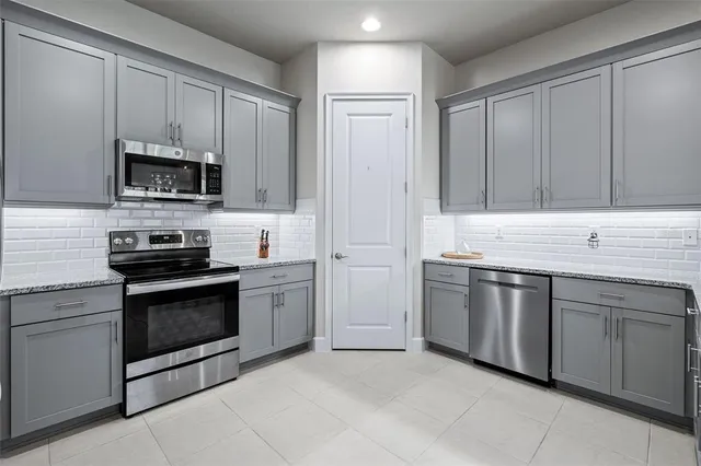 a kitchen with granite countertop white cabinets and stainless steel appliances