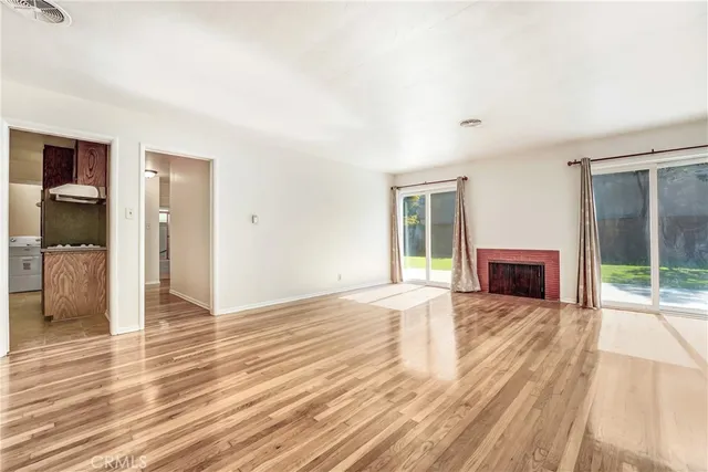 a view of a livingroom with wooden floor and a fireplace