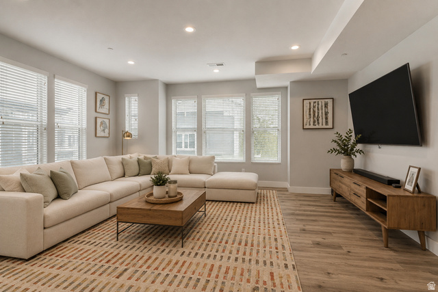 52 Golden Privet Drive Draper, UT 84020 - Photo 8 of 22 Virtually staged Spacious living area featuring wood-finish flooring, numerous windows with blinds, recessed ceiling lighting, and a contemporary media console