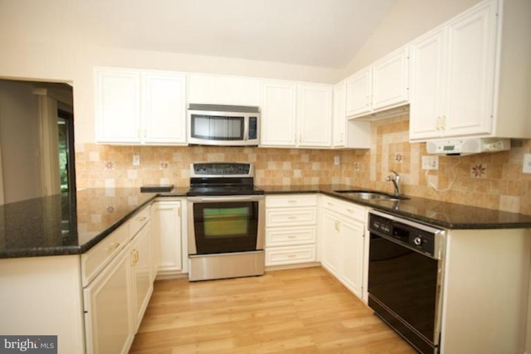 11806 Tree Fern Court Reston, VA 20191 - Photo 4 of 20 a kitchen with stainless steel appliances granite countertop a stove a sink and a microwave