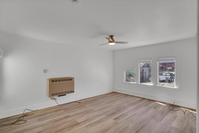 a view of an empty room with window and wooden floor