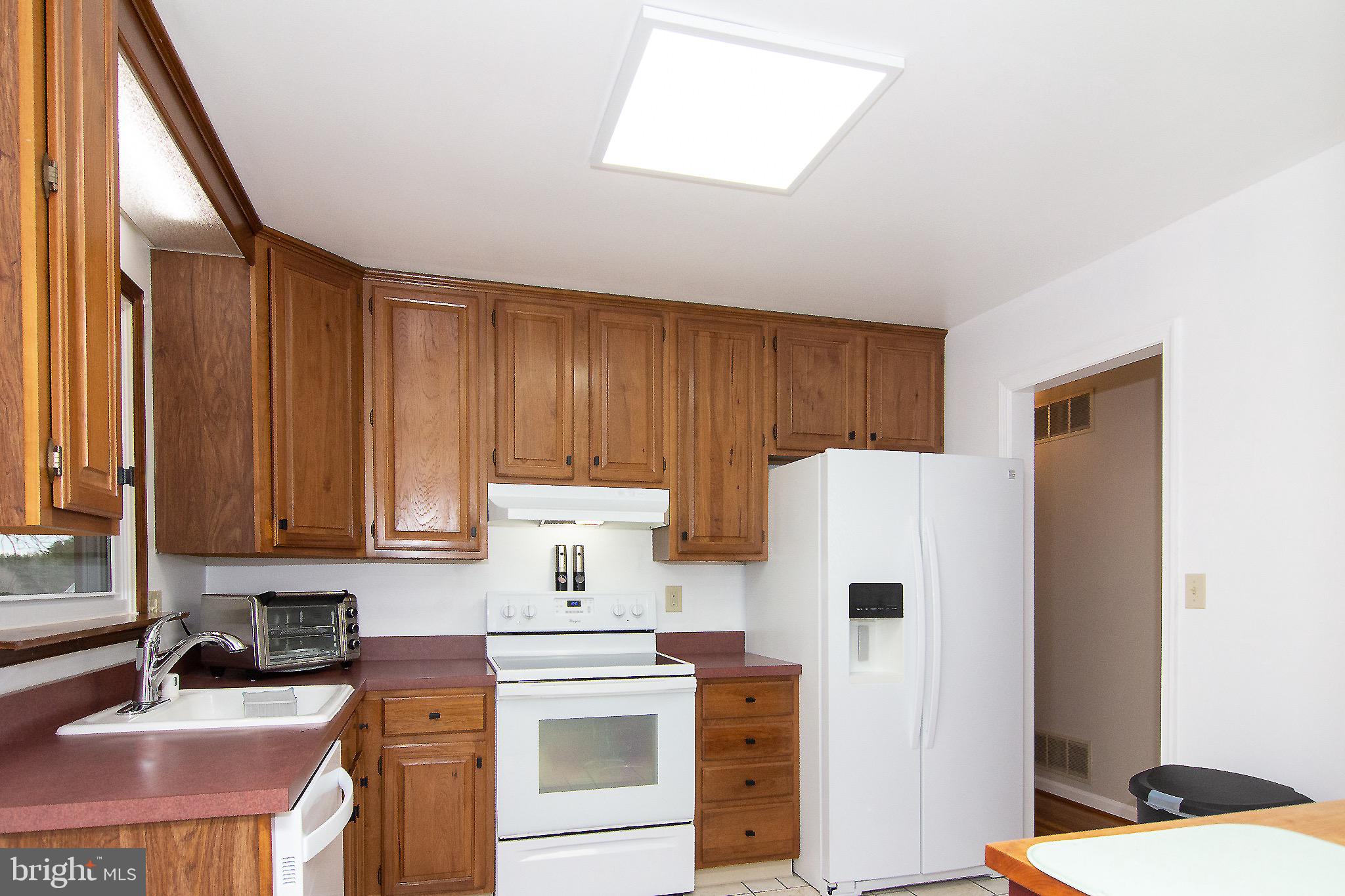 4813 Millers Station Road Hampstead, MD 21074 - Photo 8 of 32 a kitchen with a sink a refrigerator and cabinets