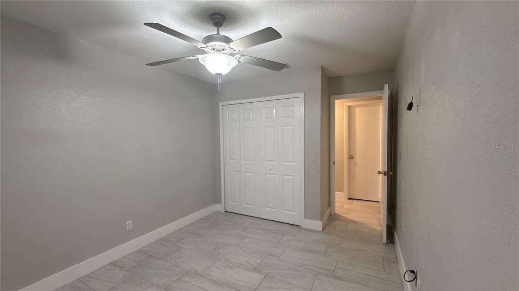 8106 Wichita Way Tampa, FL 33619 - Photo 17 of 21 an empty room with a chandelier fan and windows