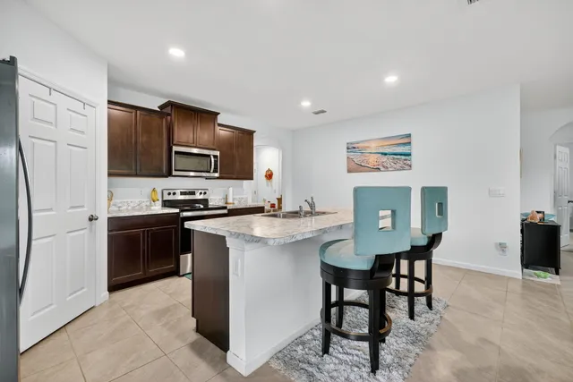 a kitchen with stainless steel appliances a stove a sink a refrigerator a dining table and chairs