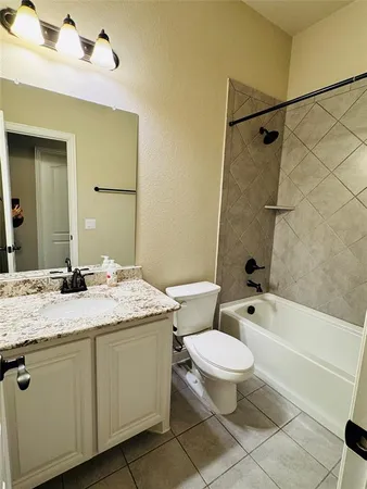 a bathroom with a granite countertop sink toilet mirror vanity and bathtub