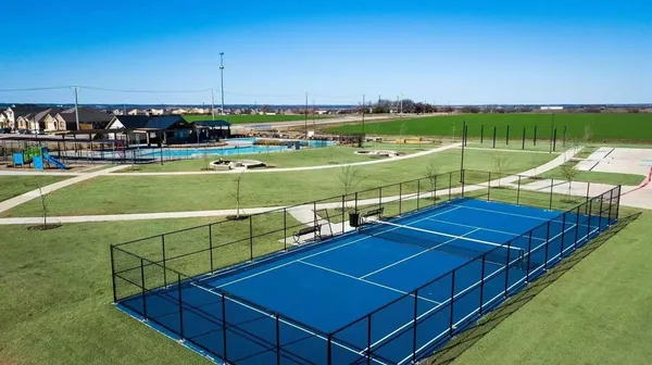 a view of a tennis ground with large trees