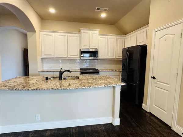 a kitchen with granite countertop cabinets and refrigerator