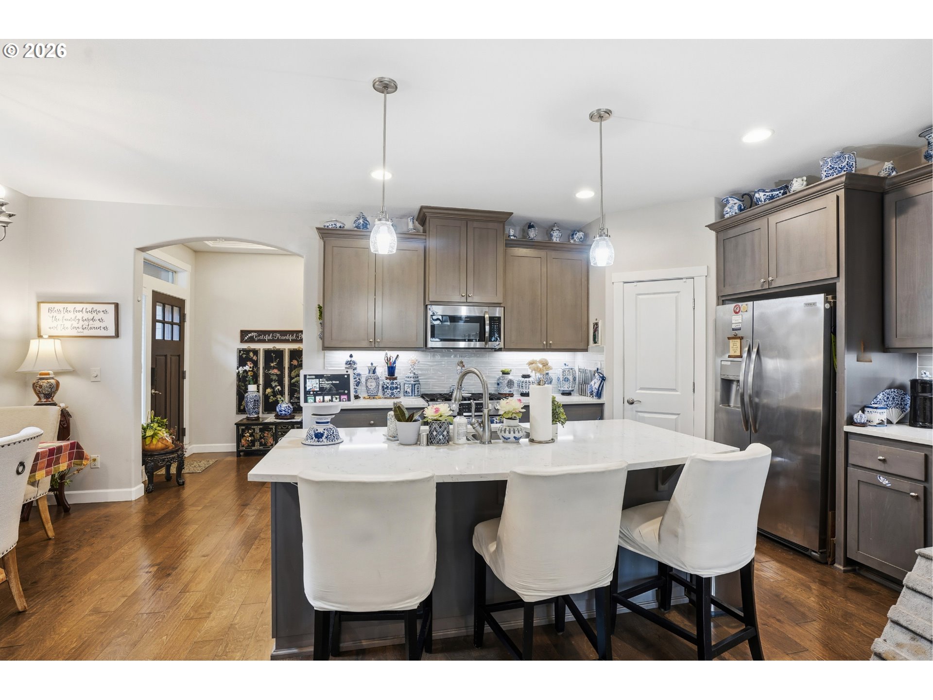 17314 Northeast 17th Avenue Ridgefield, WA 98642 - Photo 2 of 25 a kitchen with stainless steel appliances kitchen island granite countertop a dining table chairs refrigerator and microwave