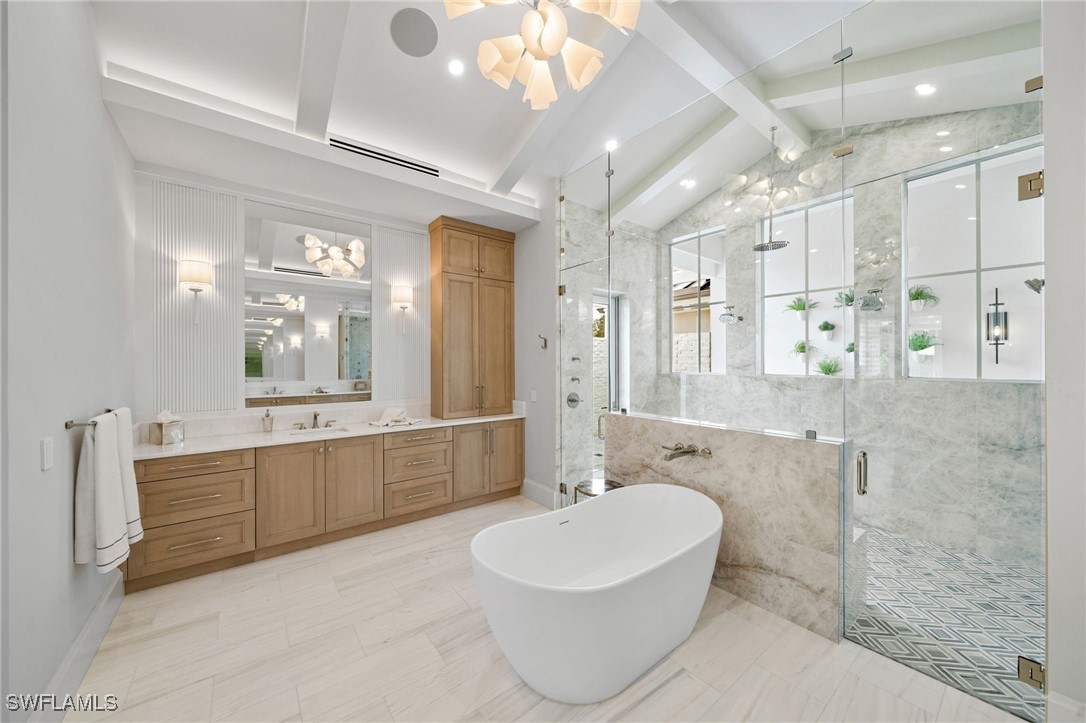 39 Cajeput Drive Naples, FL 34108 - Photo 23 of 50 a large spacious bathroom with a double vanity sink a large mirror and a bathtub