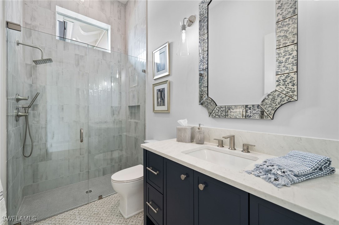 39 Cajeput Drive Naples, FL 34108 - Photo 28 of 50 a bathroom with a granite countertop sink toilet a large mirror and shower