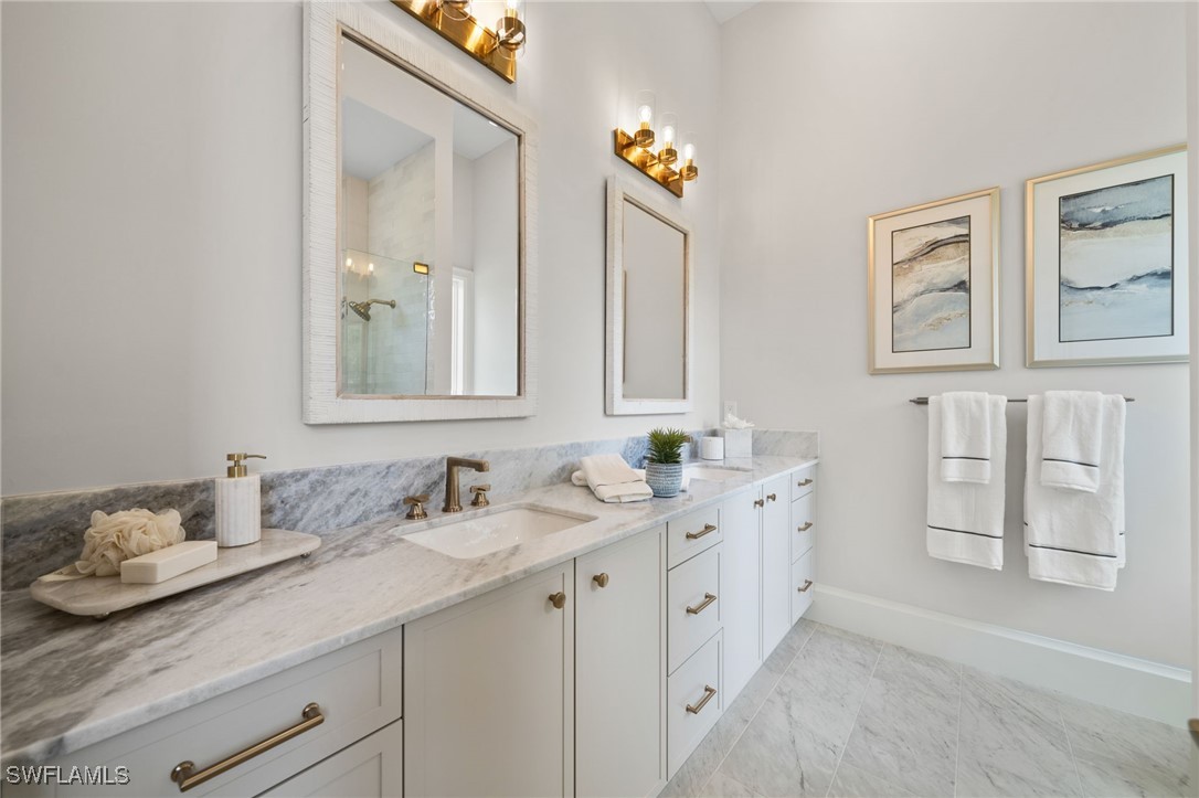 39 Cajeput Drive Naples, FL 34108 - Photo 32 of 50 a bathroom with double vanity sinks a mirror and a