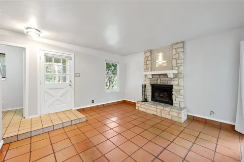 a view of an empty room with window and fireplace